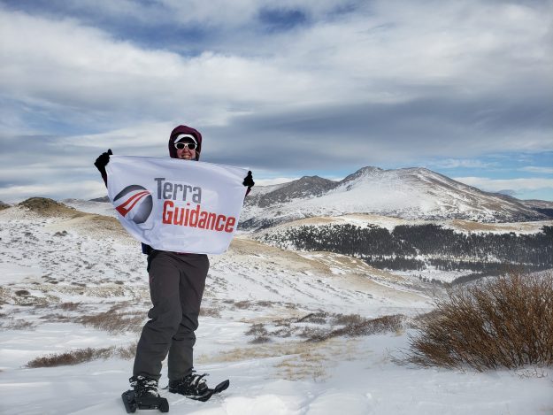 Team Member holding Terra Guidance flag within large geological landscape